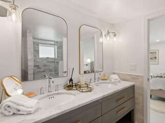 This modern bathroom features a spacious double vanity with marble countertops and sleek gray cabinetry.