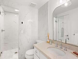 Experience modern luxury in this stunning bathroom, featuring elegant marble tile throughout and a spacious walk-in shower.