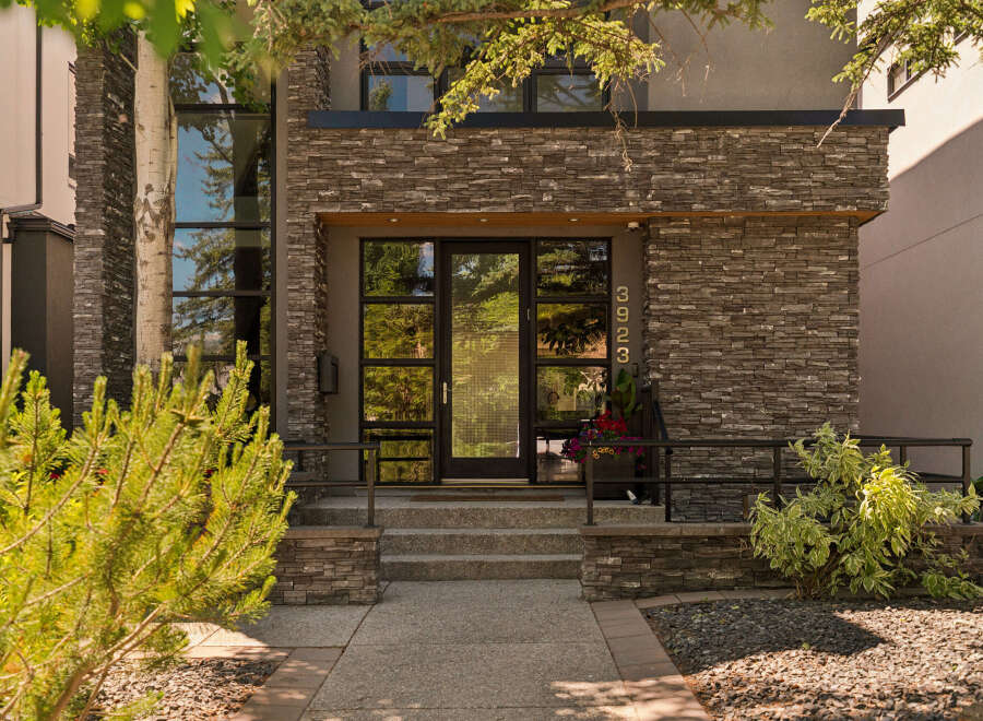 Experience modern luxury with this stunning home featuring a striking stone facade and expansive glass windows.