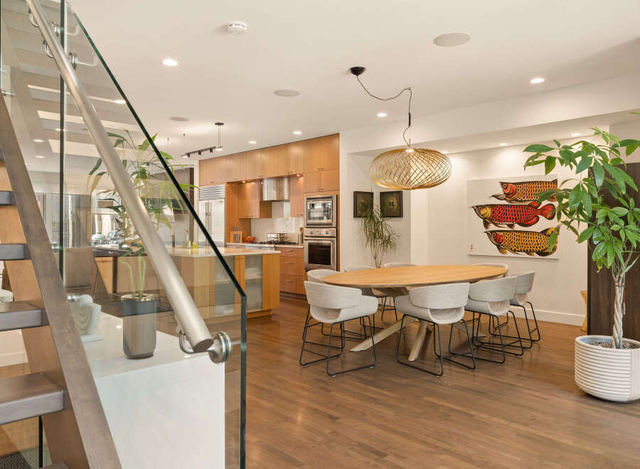 Experience modern living in this stunning open-concept space, featuring a sleek kitchen with warm wood cabinetry and stainless steel appliances.