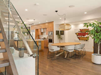 Experience modern living in this stunning open-concept space, featuring a sleek kitchen with warm wood cabinetry and stainless steel appliances.