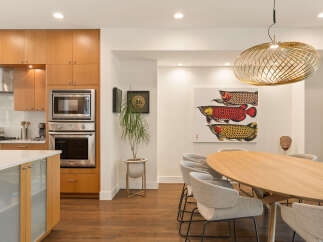 Experience modern living in this stunning kitchen and dining area, featuring sleek wood cabinetry and stainless steel appliances.