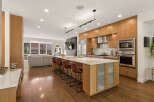 Experience modern luxury in this stunning open-concept kitchen, featuring sleek wood cabinetry, a spacious island with seating, and top-of-the-line stainless steel appliances.