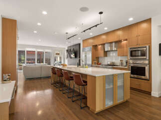 Experience modern luxury in this stunning open-concept kitchen, featuring sleek wood cabinetry, a spacious island with seating, and top-of-the-line stainless steel appliances.