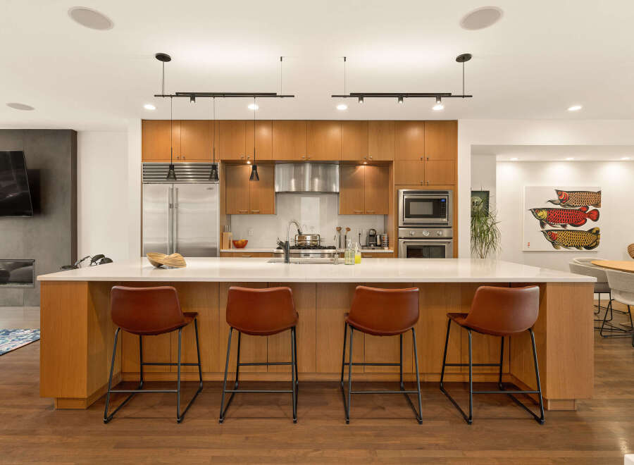 Experience modern luxury in this stunning kitchen, featuring sleek wood cabinetry, a spacious quartz island with bar seating, and top-of-the-line stainless steel appliances.