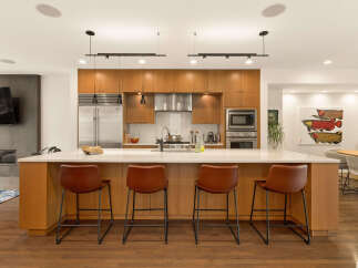 Experience modern luxury in this stunning kitchen, featuring sleek wood cabinetry, a spacious quartz island with bar seating, and top-of-the-line stainless steel appliances.