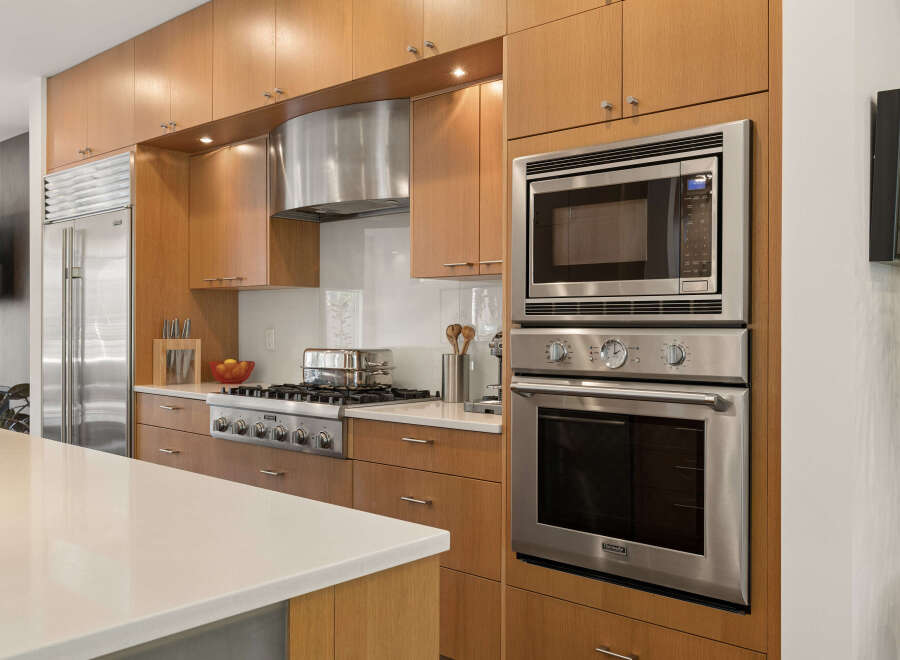 Experience culinary excellence in this modern kitchen, featuring sleek stainless steel appliances including a built-in oven and microwave, complemented by a professional-grade gas range.