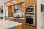 Experience culinary excellence in this modern kitchen, featuring sleek stainless steel appliances including a built-in oven and microwave, complemented by a professional-grade gas range.