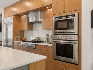 Experience culinary excellence in this modern kitchen, featuring sleek stainless steel appliances including a built-in oven and microwave, complemented by a professional-grade gas range.