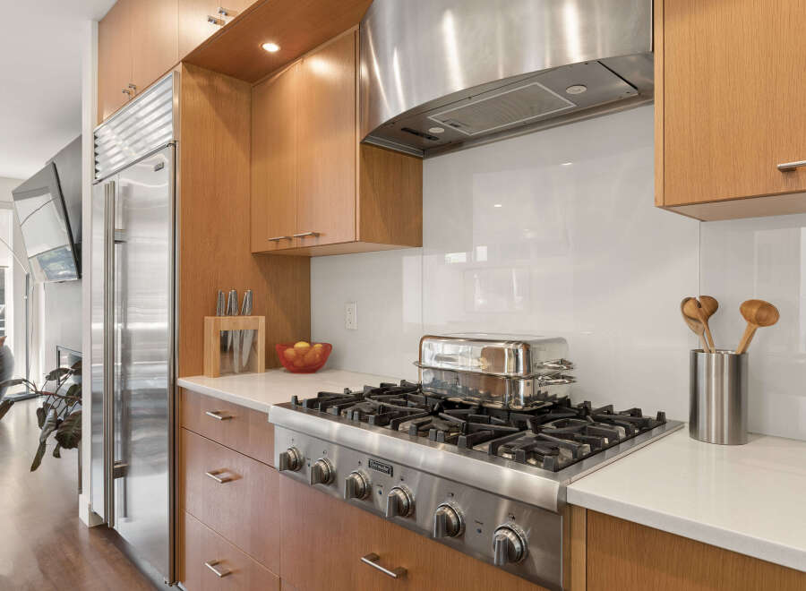 Experience culinary excellence in this modern kitchen, featuring a professional-grade gas range and a sleek stainless steel range hood.