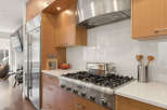 Experience culinary excellence in this modern kitchen, featuring a professional-grade gas range and a sleek stainless steel range hood.