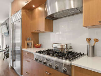 Experience culinary excellence in this modern kitchen, featuring a professional-grade gas range and a sleek stainless steel range hood.