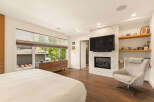 Experience luxury living in this master suite featuring a modern gas fireplace with marble surround and a wall-mounted television.