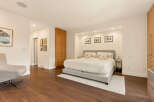 This spacious bedroom features a comfortable king-sized bed with plush pillows, set against a backdrop of recessed lighting and framed artwork.