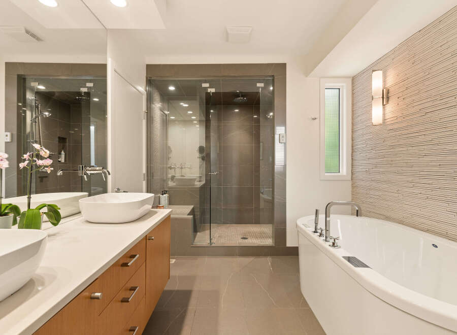 Experience luxury in this modern bathroom featuring a freestanding soaking tub and a spacious glass-enclosed shower with sleek tilework.