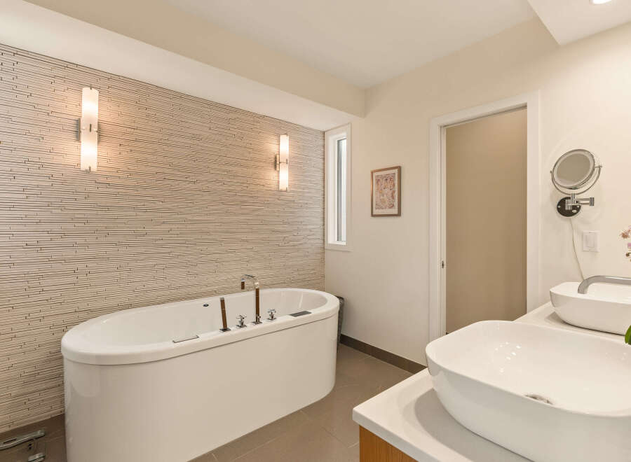 Experience ultimate relaxation in this luxurious bathroom, featuring a deep soaking tub set against a textured stone accent wall.
