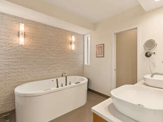 Experience ultimate relaxation in this luxurious bathroom, featuring a deep soaking tub set against a textured stone accent wall.