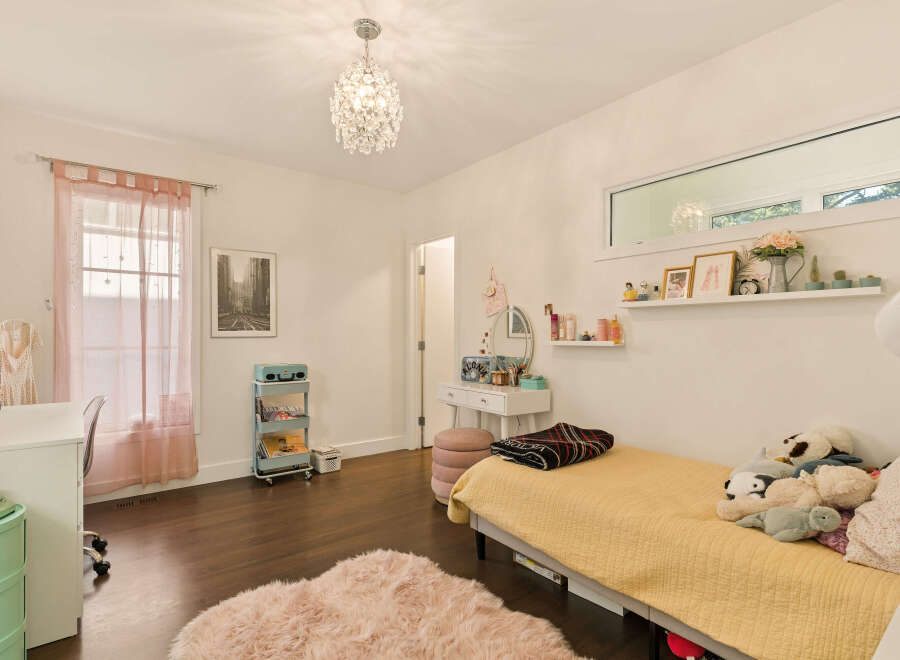 This charming bedroom features a cozy bed with a yellow quilt and a collection of plush toys, perfect for a child or teen.
