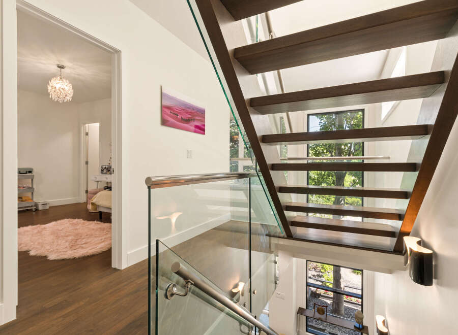 Experience modern luxury with this stunning staircase featuring floating wooden treads and sleek glass railings.
