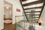 Experience modern luxury with this stunning staircase featuring floating wooden treads and sleek glass railings.