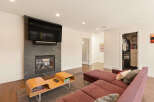 Experience modern living in this stylish living room featuring a sleek fireplace with an integrated TV and a contemporary wood coffee table.