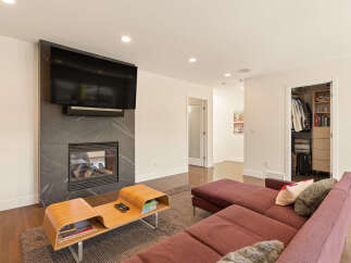 Experience modern living in this stylish living room featuring a sleek fireplace with an integrated TV and a contemporary wood coffee table.