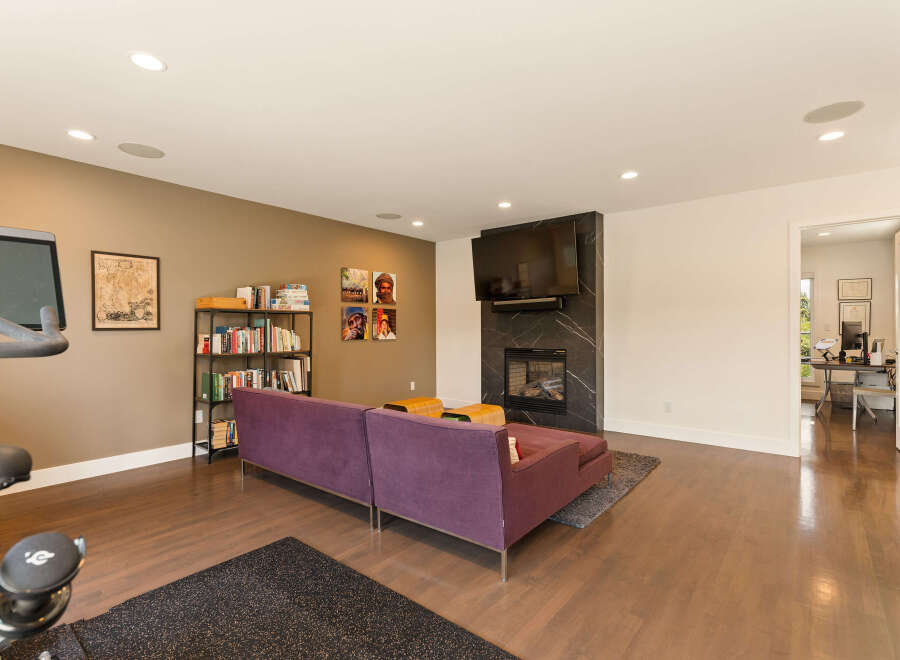 This spacious living area features a modern entertainment setup with a large flat-screen TV mounted above a sleek fireplace.
