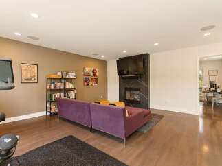 This spacious living area features a modern entertainment setup with a large flat-screen TV mounted above a sleek fireplace.