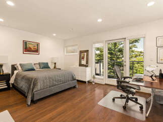 This spacious bedroom offers a comfortable king-sized bed with a quilted grey comforter and plush teal pillows, perfect for relaxation.