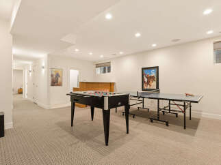 This finished basement offers a fantastic entertainment space, complete with a foosball table and a ping pong table for endless fun.