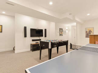 This finished basement offers a fantastic entertainment space, complete with a foosball table and a ping pong table for endless fun.