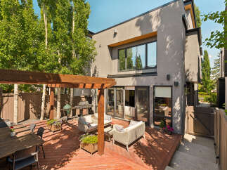 Enjoy outdoor living in this stunning backyard featuring a spacious wooden deck, a covered pergola, and a dining area perfect for al fresco meals.