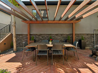 Enjoy outdoor living with this spacious deck featuring a modern pergola, perfect for al fresco dining.