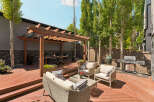 Enjoy outdoor living with this spacious wooden deck, featuring a covered pergola for shade and a dining area.