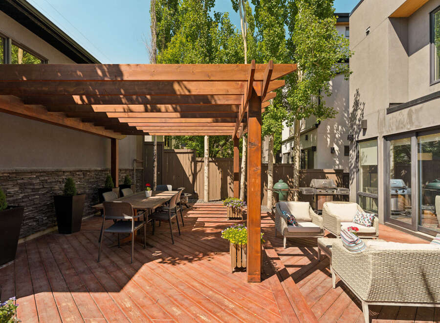 Enjoy outdoor living with this spacious patio featuring a large wooden pergola, perfect for al fresco dining.