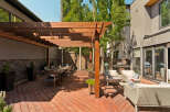 Enjoy outdoor living with this spacious patio featuring a large wooden pergola, perfect for al fresco dining.