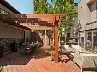 Enjoy outdoor living with this spacious patio featuring a large wooden pergola, perfect for al fresco dining.
