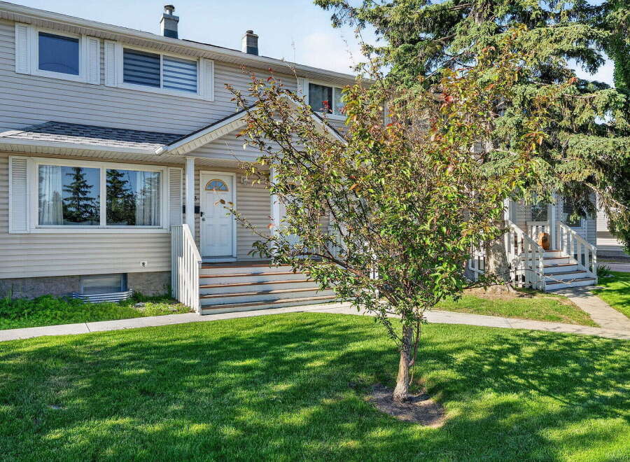 Charming townhouse with a welcoming front entrance, featuring a white door and steps leading up to the porch.
