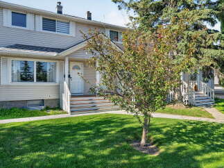 Charming townhouse with a welcoming front entrance, featuring a white door and steps leading up to the porch.