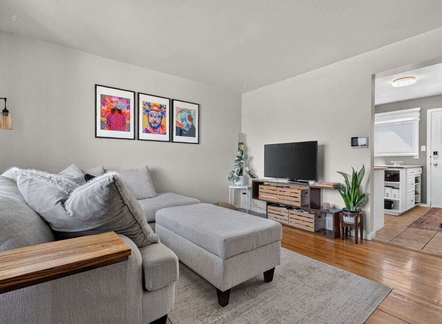 Step into this inviting living room featuring a comfortable sectional sofa with plush pillows and a stylish ottoman, perfect for relaxation.