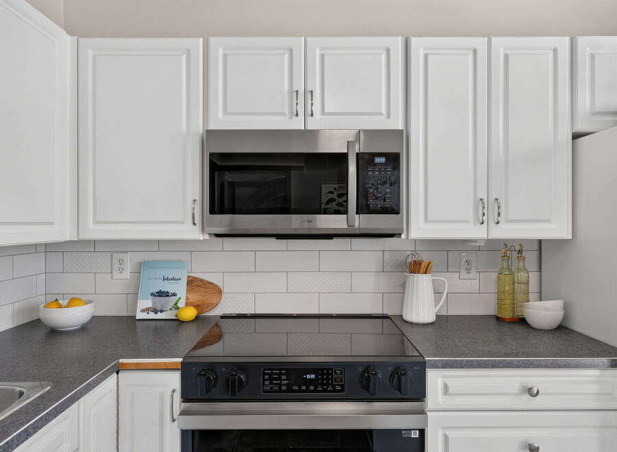 This kitchen features sleek white cabinetry and a modern stainless steel microwave, creating a bright and airy atmosphere.