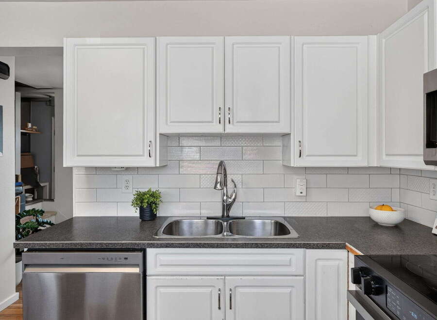 This kitchen features a sleek stainless steel dishwasher and a double basin sink, perfect for any home chef.