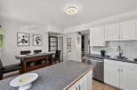 This spacious kitchen features white cabinetry, a sleek stainless steel dishwasher, and a double sink with a modern faucet.
