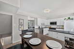 This spacious kitchen features white cabinetry, a sleek black countertop, and a convenient breakfast bar area perfect for casual dining.