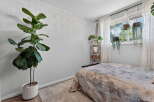 Brighten your space with this serene bedroom, featuring a large fiddle leaf fig plant and a collection of hanging plants by the window.