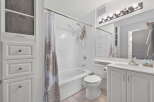 This bright and clean bathroom features a white tiled shower-tub combination with a patterned shower curtain.