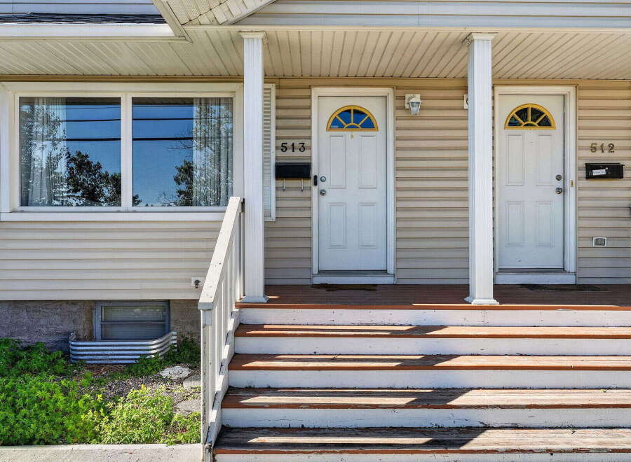 Charming duplex featuring two separate entrances, each with a welcoming porch and a distinctive arched window above the door.