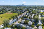Discover this charming residential neighborhood featuring a baseball field and a distant city skyline.