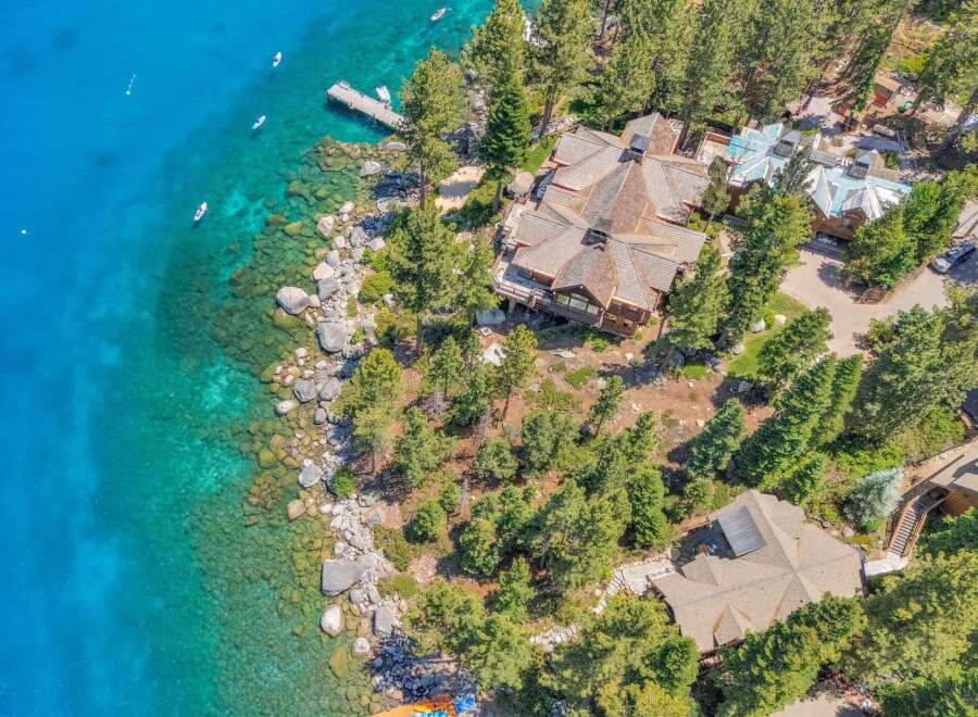 Experience luxury lakeside living in this stunning property featuring a sprawling estate with multiple buildings, a private dock, and direct access to crystal-clear turquoise waters.