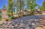 Discover this stunning property featuring a grand stone entrance with a curved wall adorned with vibrant flowers, leading to a beautiful wooden home.